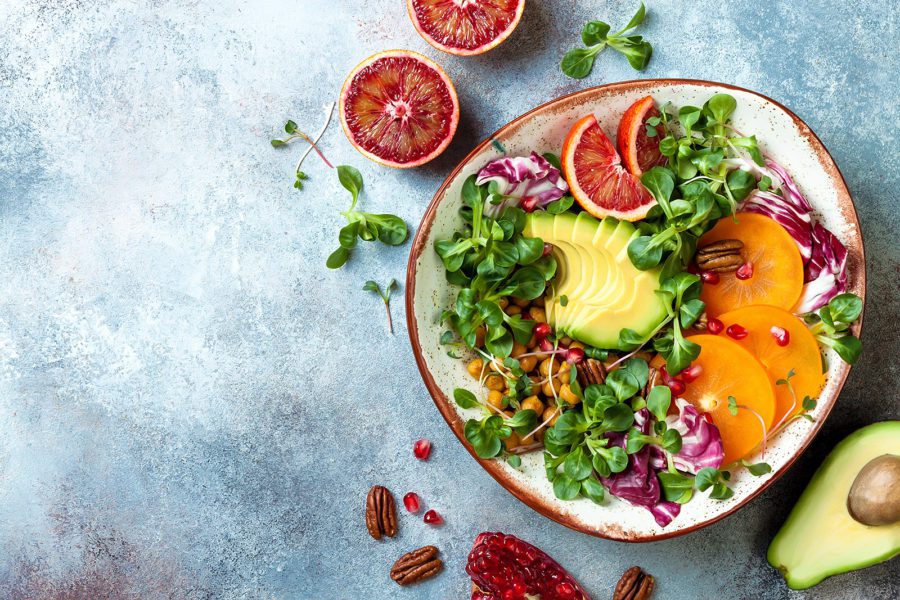 vegan-detox-buddha-bowl-with-turmeric-roasted-chickpeas-greens-avocado-persimmon-blood-orange-nuts-and-pomegranate-top-view-flat-lay