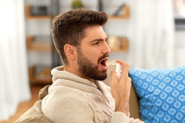 Man applying spray in to his mouth