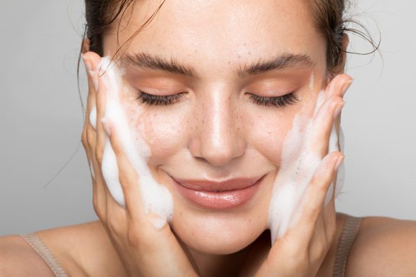 Close up studio shot of a beautiful woman with perfect skin, while she cleaning her face