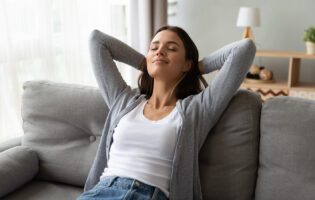 Relaxed Serene Young Woman Lounge On Comfortable Sofa At Home