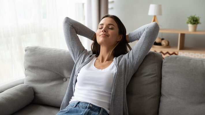 Relaxed Serene Young Woman Lounge On Comfortable Sofa At Home