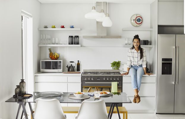 Portrait Of Happy Woman Sitting On Kitchen Counter