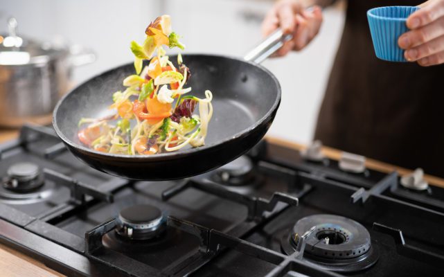 chef throwing veggies and meat in the wok