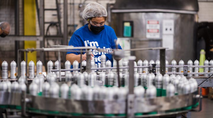 Female PLZ employee working with aerosol cans on conveyor belt