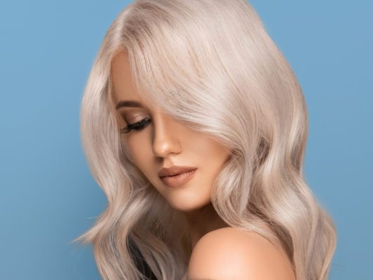 young white women with platinum blonde hair in front of blue background